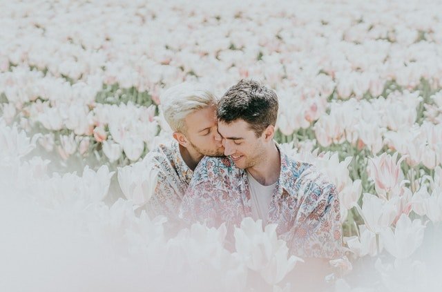 Couple de jeunes hommes dans un champ de fleur, tendrement enlacé